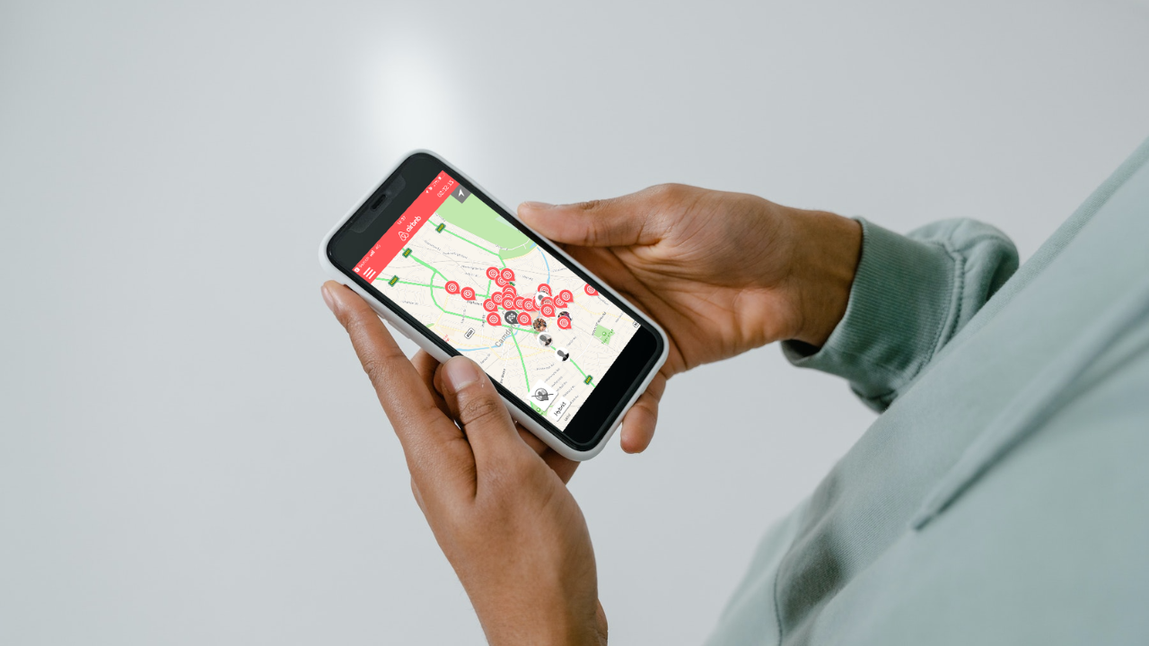 A leader holding a phone running the Airbnb Expedition app, with a live map of team locations